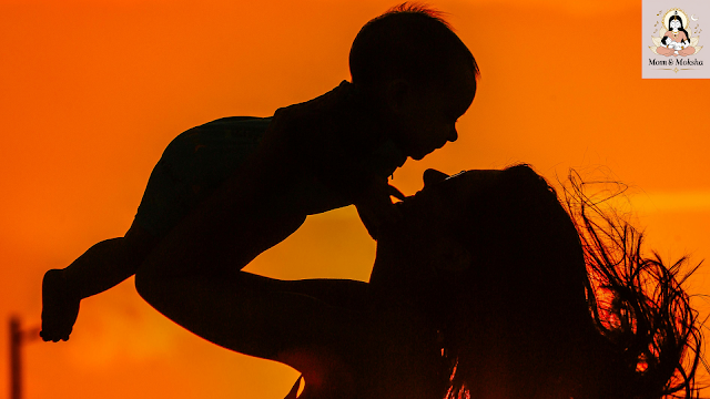 Mom holding sleeping baby with OM symbol in soft background light